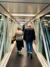 Rear view of senior couple walking on passenger boarding bridge