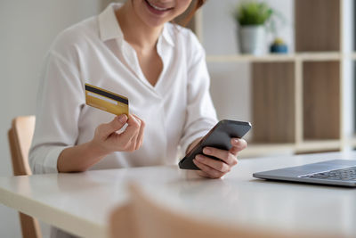 Midsection of woman using smart phone on table