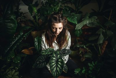 Portrait of young woman standing against plants