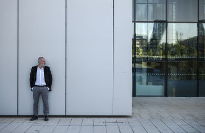 Portrait of adult man in suit against white wall in financial district