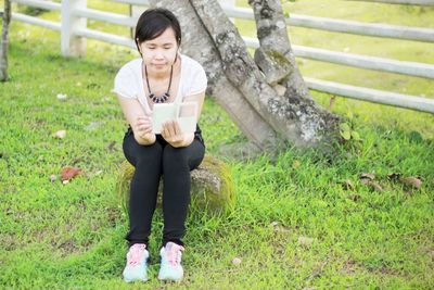 Full length of young woman sitting on field