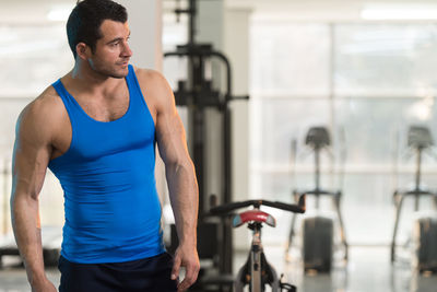 Muscular man wearing vest standing in gym