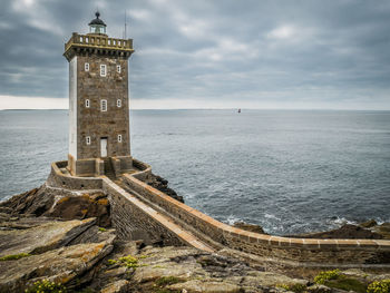 Lighthouse by sea against sky