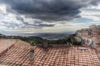 Houses by sea against sky in town