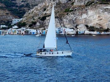 Sailboat sailing on sea against mountain