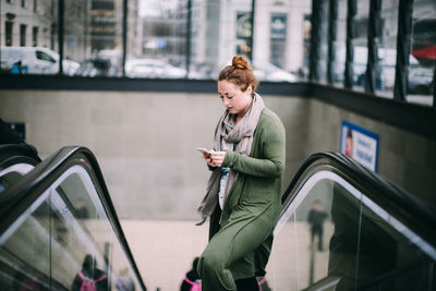 Full length of young woman looking through mobile phone