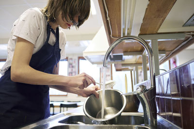 Young woman in kitchen washing dishes