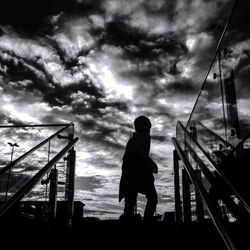 Low angle view of man standing against cloudy sky