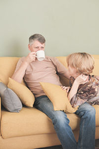 Portrait of smiling friends sitting on sofa at home