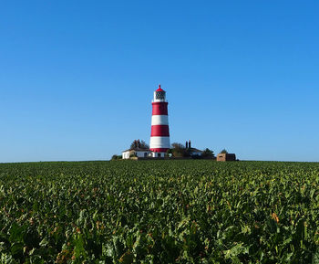 Lighthouse on field against sky