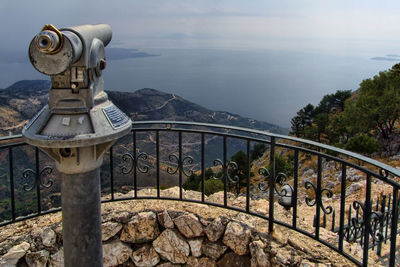 Coin-operated binoculars at observation point on mountain by sea