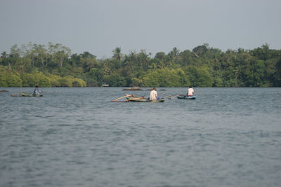 People in boat on lake against sky