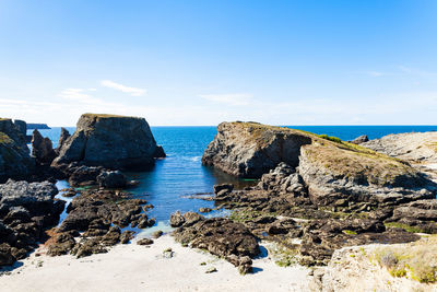 Rocks on beach against blue sky