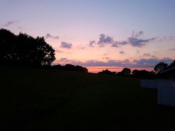 Silhouette trees on field against sky at sunset