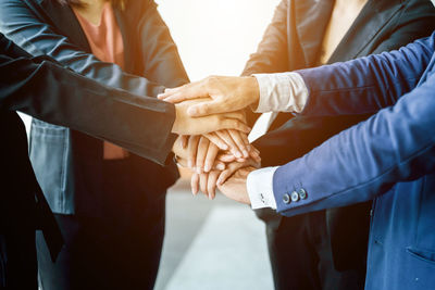 Midsection of business people stacking hands