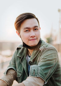 Portrait of young man sitting against sky