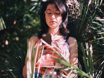 Young woman photographing with mobile phone outdoors