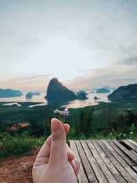 Midsection of person hand holding mountain against sky
