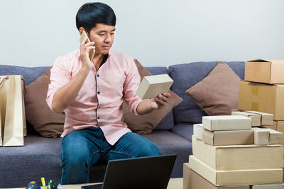 Young man using mobile phone while sitting on sofa