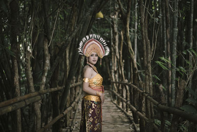 Woman standing by tree in forest