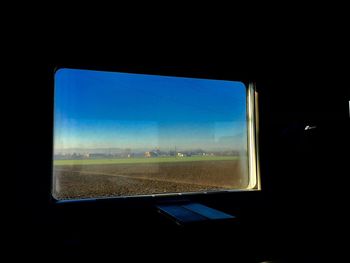View of landscape against blue sky seen through car window