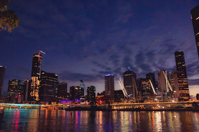 Illuminated buildings in city against sky at night