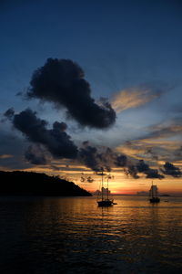 Silhouette sailboats in sea against sky during sunset