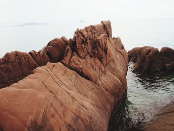 Rock formation by sea against sky