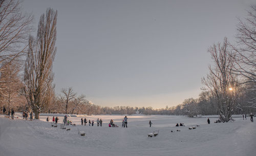 People on snow covered field against sky