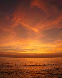 Scenic view of sea against dramatic sky during sunset