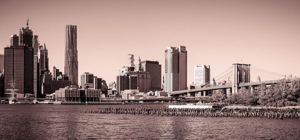 Bridge over river by buildings in city against sky