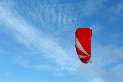 Low angle view of red kite parachute against blue sky