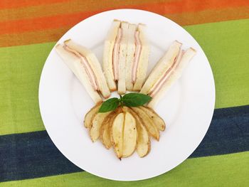 Directly above shot of potato chips and sandwiches in plate on table