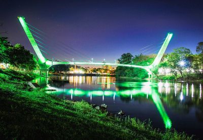 Illuminated bridge over river against sky at night