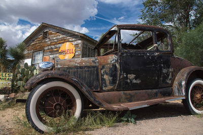 Abandoned car on land against sky