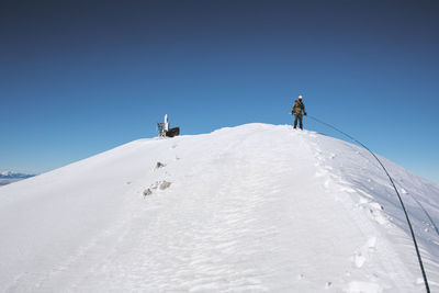 Man on snow covered mountain against clear sky