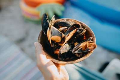 Close-up of hand holding bowl with mussels