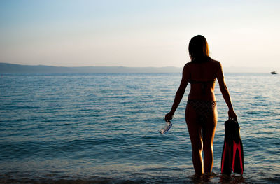 Rear view of young woman walking on beach