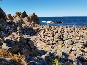 Rock formations in sea against clear blue sky