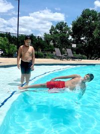 Shirtless boy looking at friend falling in swimming pool