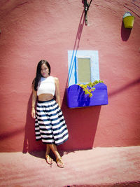 Portrait of young woman standing against wall