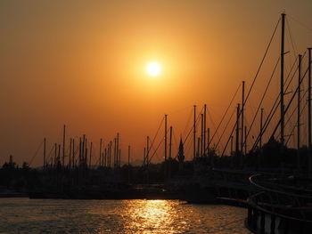 Sailboats in sea at sunset