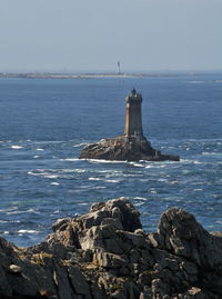 Lighthouse by sea against clear sky