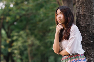 Young woman standing against trees