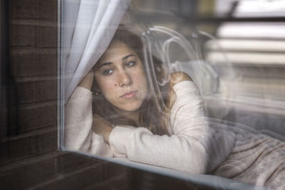 Portrait of a young woman sitting in window