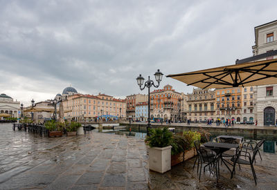 Sidewalk cafe by buildings in city against sky