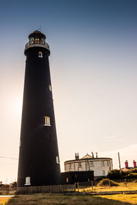 Low angle view of lighthouse by building against clear sky