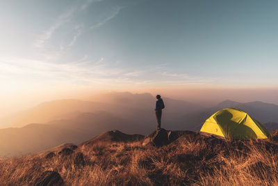 Man standing on mountain against sky during sunrise