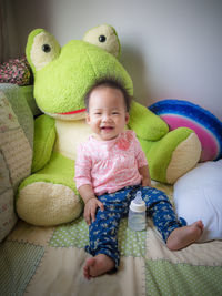 Cute baby girl sitting with toy at home