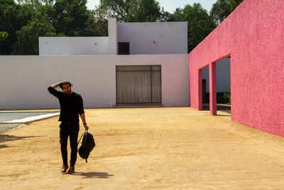 Person in architectural work of luis barragan, boy dressed in black, on sand,